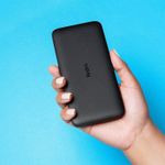 Batería externa Xiaomi Redmi 20000 mAh 18W negro sostenida por una mano con fondo azul claro