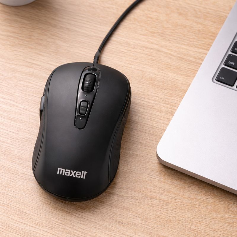 Mouse alámbrico Maxell MOWR-105C en color negro sobre escritorio de madera junto a laptop cenital