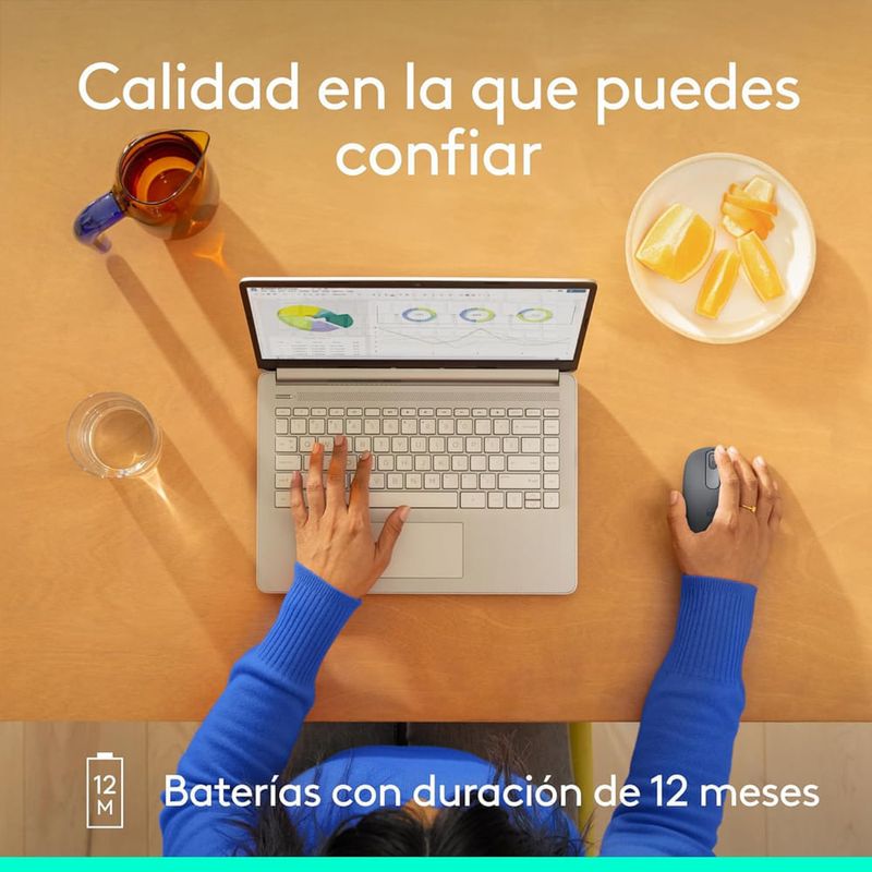 Mouse inalámbrico Logitech M196 en uso con laptop sobre escritorio y texto sobre duración de batería de 12 meses vista cenital