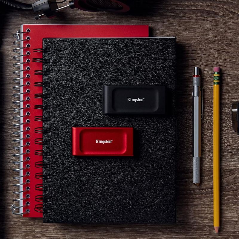 SSD externo Kingston XS1000 1TB Negro Frontal-oblicuo sobre cuaderno y accesorios de trabajo