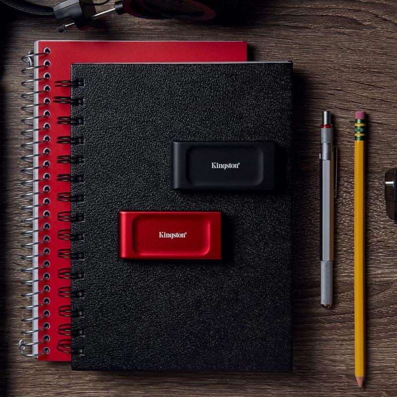 SSD externo Kingston XS1000 2TB Rojo Frontal-oblicuo sobre cuaderno y accesorios de trabajo