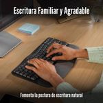 Teclado ergonómico inalámbrico Logitech Wave Keys Ergo, diseño ondulado ergonómico con reposamanos acolchado, color negro, vista en uso, sobre escritorio de madera con manos escribiendo