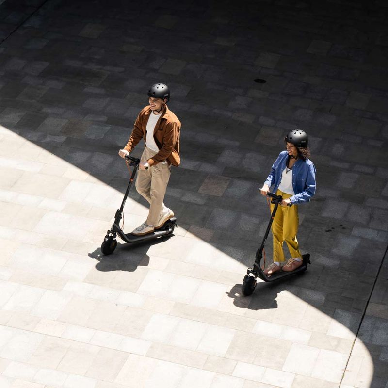 Scooter eléctrico Segway Ninebot E2 Plus II 8.1", autonomía hasta 25km, velocidad máxima 25 km/h, tiempo de carga 7 horas, ángulo picado con dos personas en scooter.